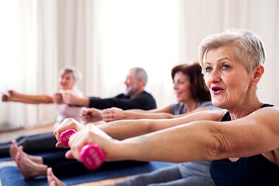 Group of senior people doing exercise with dumbbells in community center club.